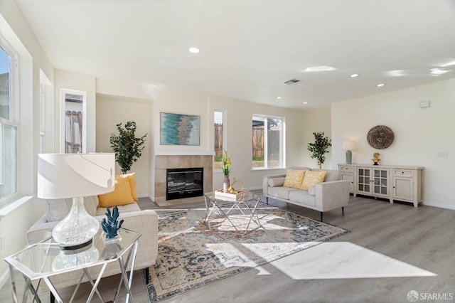 living room with baseboards, visible vents, a tile fireplace, wood finished floors, and recessed lighting