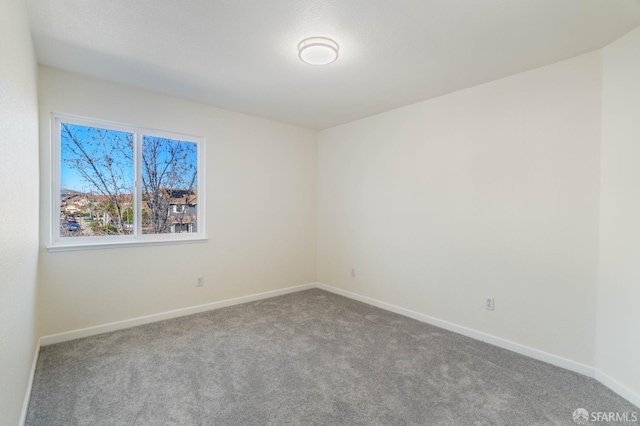 carpeted empty room featuring baseboards