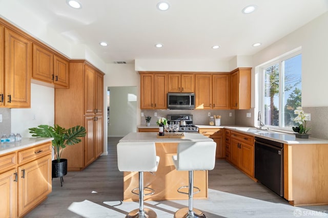 kitchen with stainless steel appliances, a center island, light countertops, and light wood-style floors