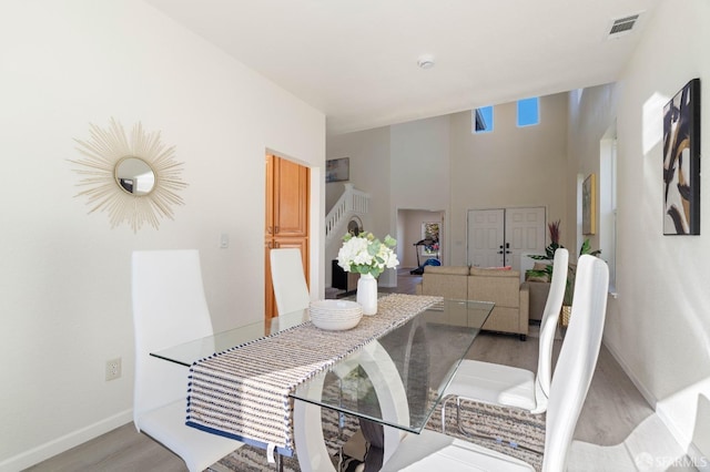 dining space featuring baseboards, visible vents, stairway, and light wood finished floors