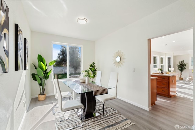 dining area featuring light wood-style flooring and baseboards