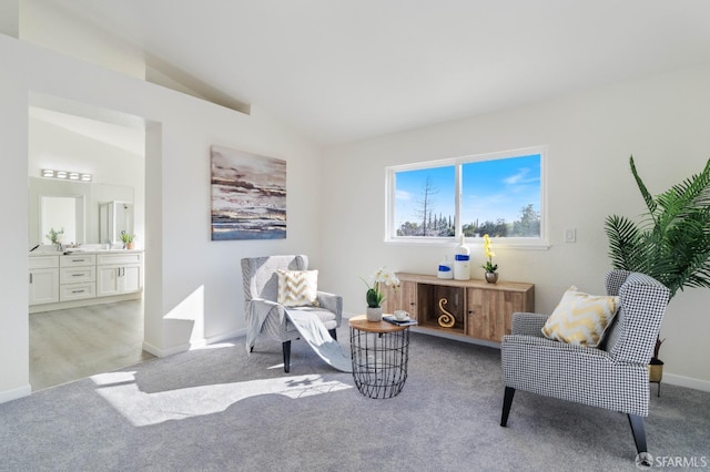 sitting room with light carpet, baseboards, and vaulted ceiling