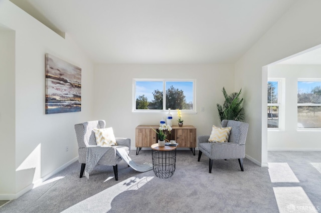 sitting room featuring a healthy amount of sunlight, light colored carpet, vaulted ceiling, and baseboards