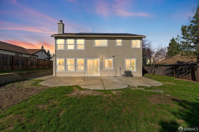 rear view of house featuring a fenced backyard, a patio, a chimney, and a lawn