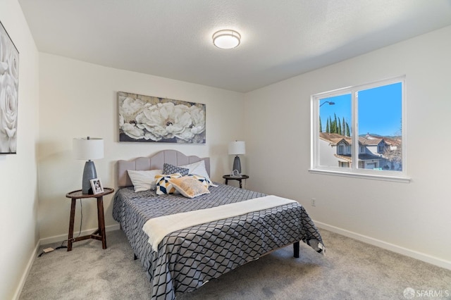 bedroom with baseboards, a textured ceiling, and light colored carpet