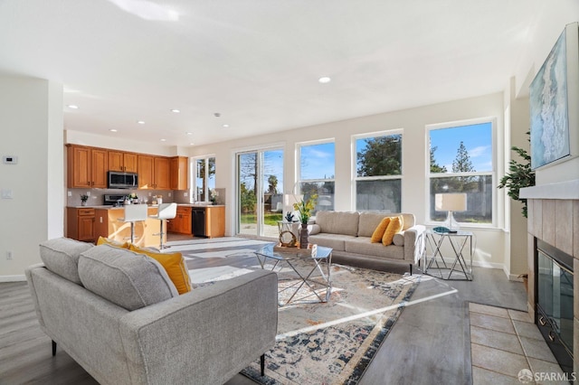 living room featuring recessed lighting, a fireplace, baseboards, and wood finished floors