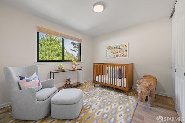 bedroom with a crib, baseboards, and wood finished floors