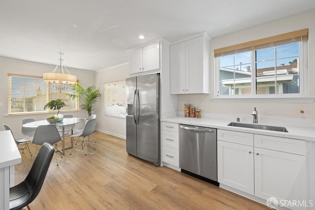 kitchen with stainless steel appliances, a sink, white cabinetry, light countertops, and light wood-type flooring