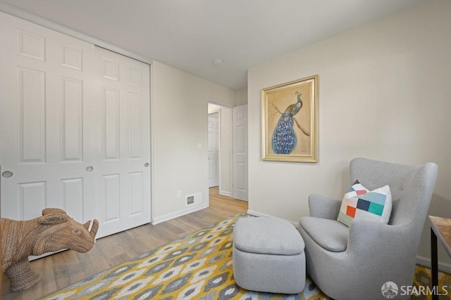 sitting room with baseboards, visible vents, and wood finished floors