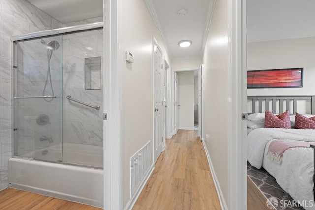 interior space featuring baseboards, visible vents, shower / bath combination with glass door, wood finished floors, and crown molding