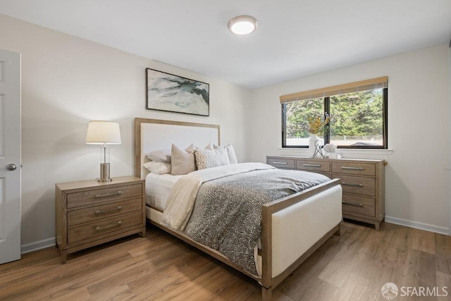 bedroom featuring light wood finished floors and baseboards