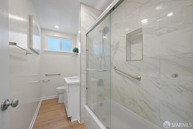 bathroom with enclosed tub / shower combo, wood finished floors, toilet, and baseboards