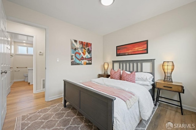 bedroom featuring baseboards, visible vents, and wood finished floors