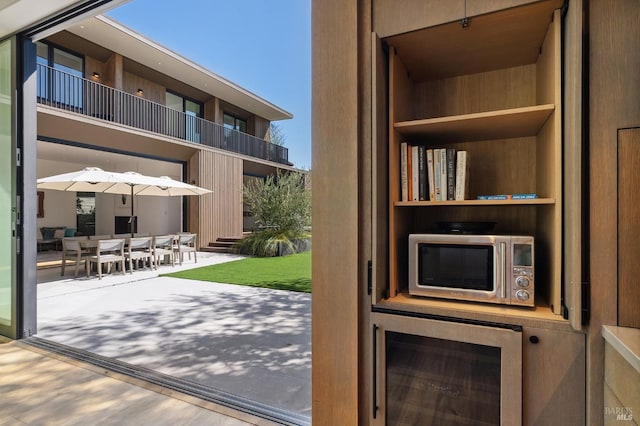 entryway with beverage cooler, a towering ceiling, and wood finished floors