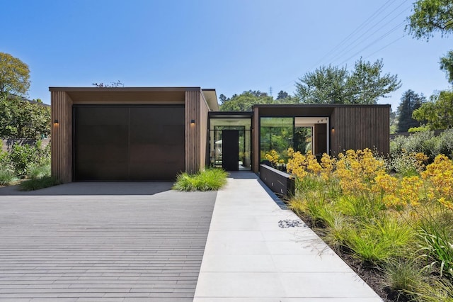 contemporary home featuring concrete driveway, an attached garage, and a gate