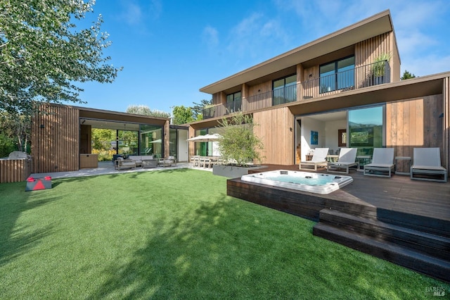 rear view of house with a patio area, hot tub deck surround, and a lawn