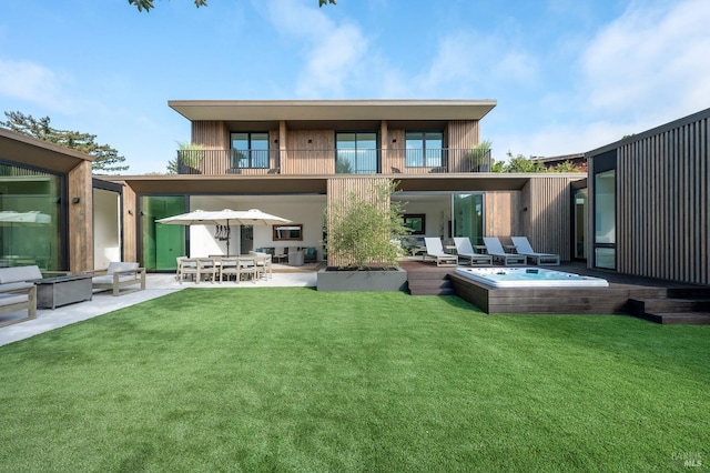 rear view of property with a lawn, a patio area, a balcony, and hot tub deck surround