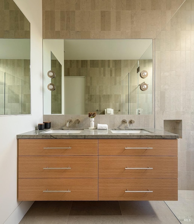 full bath with tile patterned flooring, a sink, tile walls, and double vanity