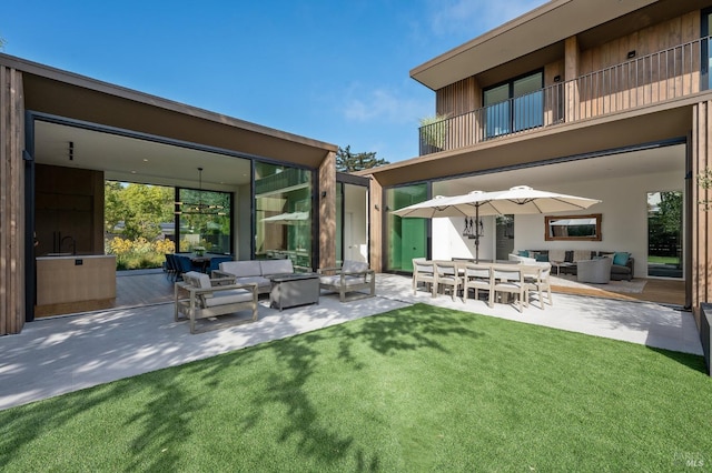 rear view of house featuring outdoor lounge area, a lawn, a balcony, and a patio