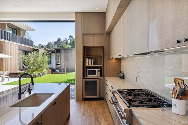 kitchen with light wood finished floors, decorative backsplash, wine cooler, stainless steel appliances, and a sink