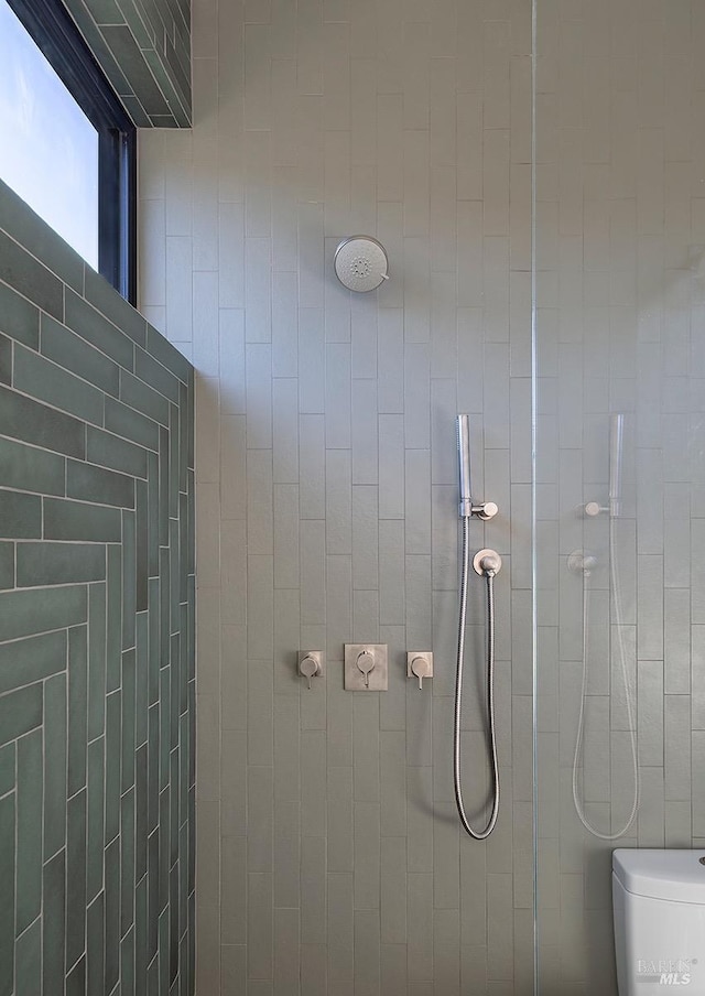 bathroom featuring tiled shower and toilet