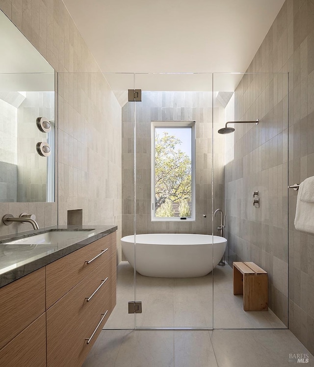 full bathroom featuring vanity, tile walls, a freestanding bath, tiled shower, and tile patterned floors