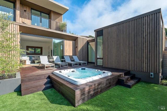 back of house with hot tub deck surround, a wooden deck, and a lawn