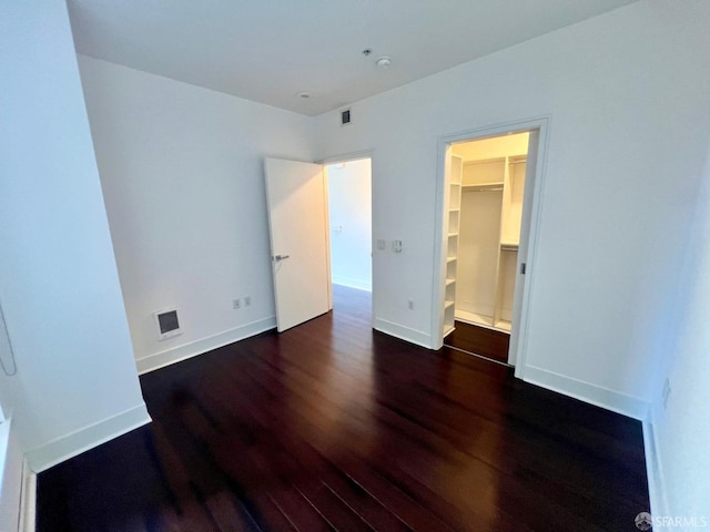 unfurnished bedroom featuring dark wood-type flooring and a walk in closet