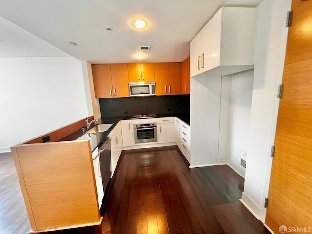 kitchen featuring sink, backsplash, appliances with stainless steel finishes, and dark hardwood / wood-style flooring