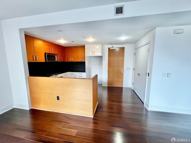 kitchen featuring dark wood-type flooring, white cabinetry, and kitchen peninsula