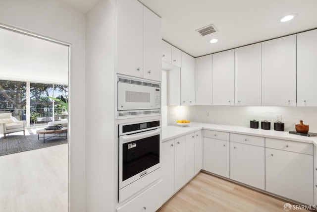 1333 Jones St Unit 508, San Francisco, CA 94109 - kitchen featuring white appliances, light wood-style floors, light countertops, tasteful backsplash, and white cabinetry