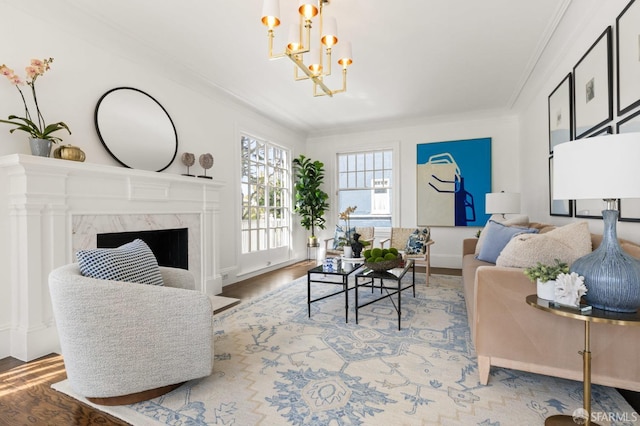 living room featuring a chandelier, a fireplace, crown molding, and wood finished floors