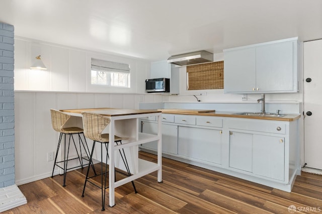 kitchen featuring dark wood-style floors, light countertops, stainless steel microwave, white cabinets, and a sink