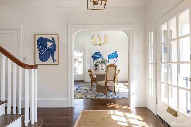 interior space with baseboards, dark wood-style floors, ornamental molding, stairs, and a notable chandelier