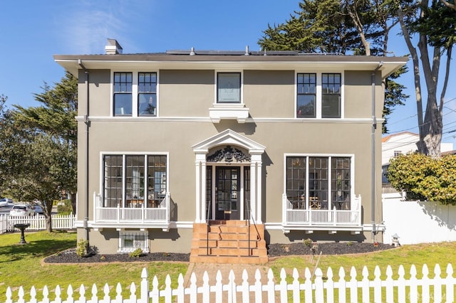 traditional-style home featuring fence private yard, solar panels, a front lawn, and stucco siding