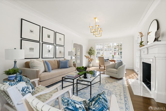 living area with a premium fireplace, ornamental molding, a chandelier, and wood finished floors