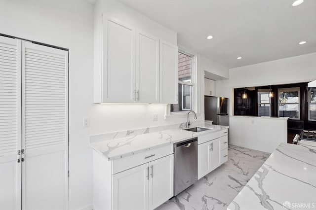 kitchen featuring white cabinetry, appliances with stainless steel finishes, light stone counters, and sink