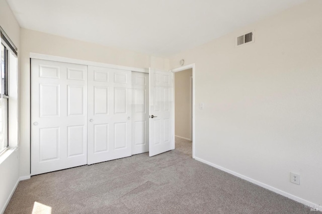 unfurnished bedroom with a closet, baseboards, visible vents, and carpet floors