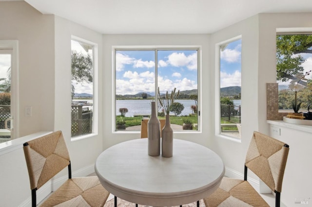 dining area with baseboards and a water view