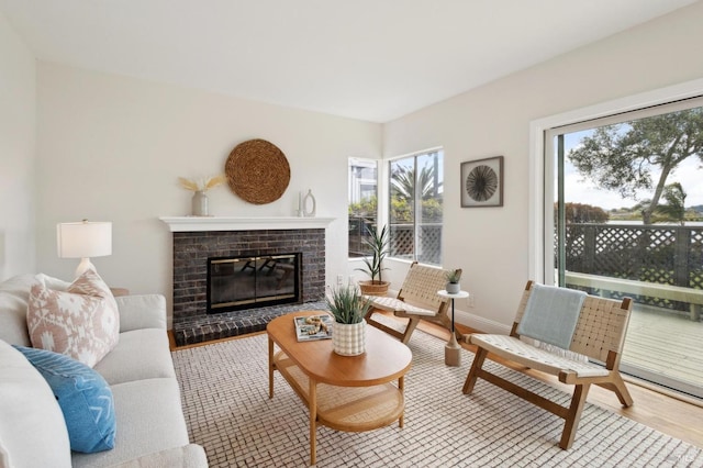 living room featuring a wealth of natural light, a brick fireplace, baseboards, and wood finished floors