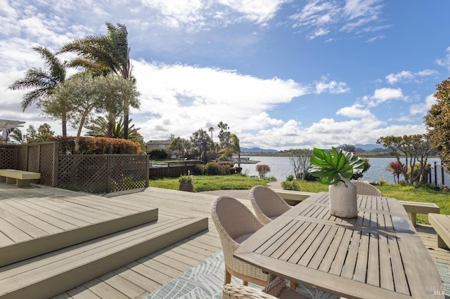 deck with a water view and outdoor dining space