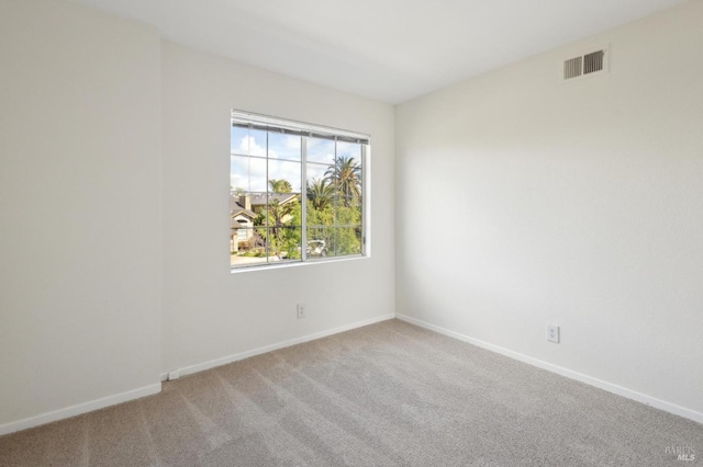 empty room featuring light carpet, visible vents, and baseboards