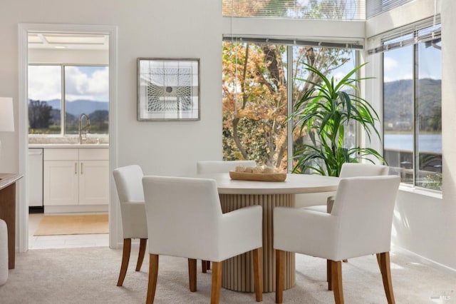 dining area featuring light carpet, light tile patterned floors, a mountain view, and baseboards