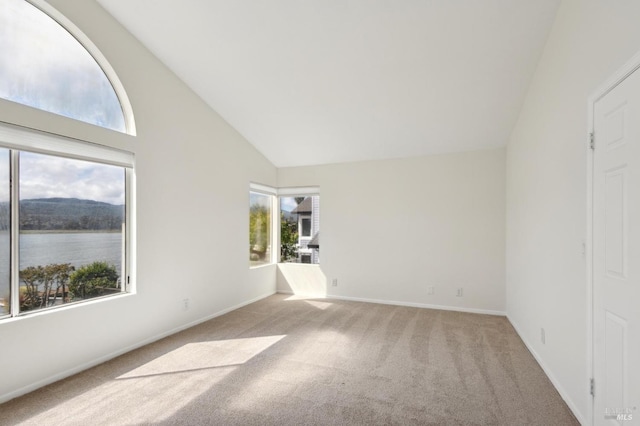 carpeted spare room featuring baseboards, a water view, and high vaulted ceiling