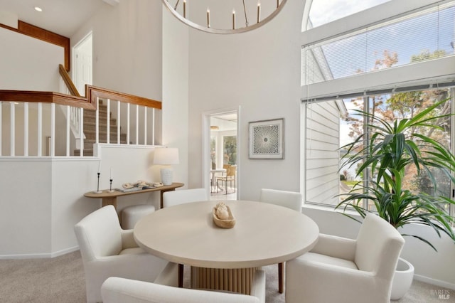 dining space featuring stairs, carpet, baseboards, and a towering ceiling