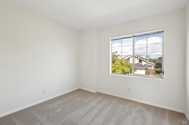 carpeted empty room featuring baseboards