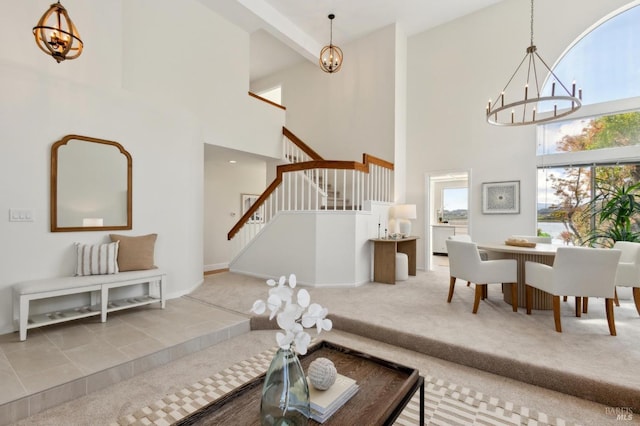 carpeted living room featuring stairs, an inviting chandelier, baseboards, and a towering ceiling