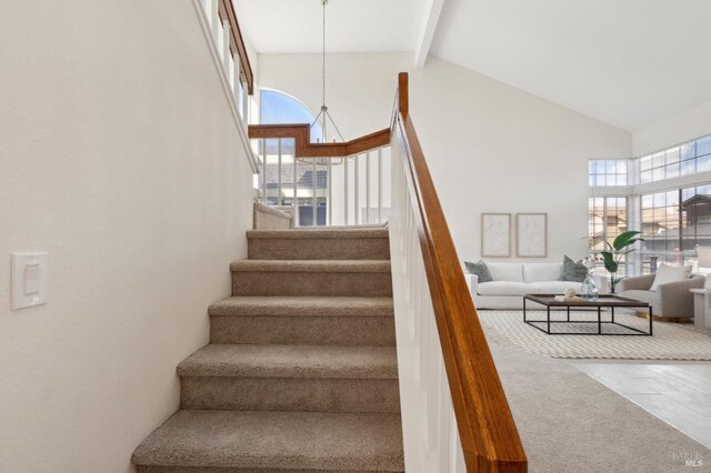 stairs with tile patterned flooring, beamed ceiling, and high vaulted ceiling