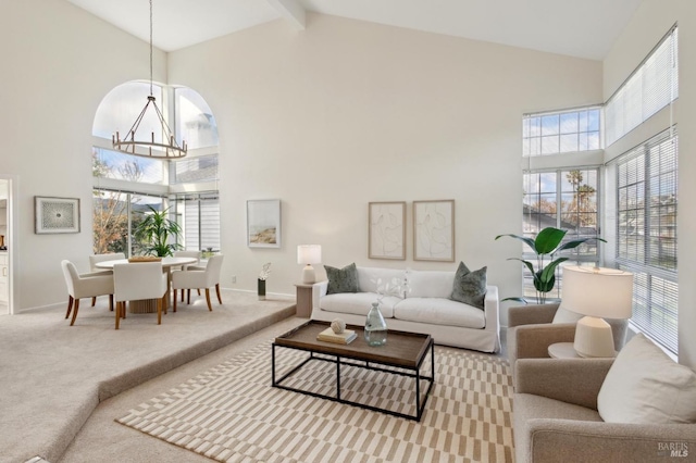 living room with beam ceiling, high vaulted ceiling, carpet, an inviting chandelier, and baseboards