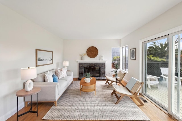 living area with visible vents, baseboards, light wood-style floors, and a fireplace